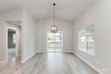 Unfurnished dining area featuring lofted ceiling, healthy amount of natural light, light wood-type flooring, and a chandelier