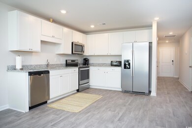 Kitchen with stainless steel appliances, white cabinetry, and light wood-type flooring