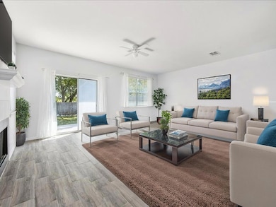 Living room featuring a fireplace, light wood-type flooring, and ceiling fan