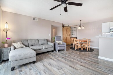 Living area featuring a barn door, a ceiling fan, newly installed LVP flooring, baseboards, and a chandelier
