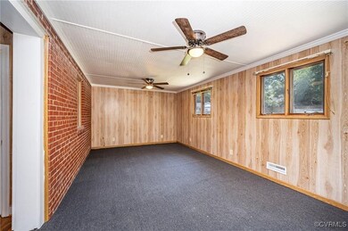 Spare room with wooden walls, ceiling fan, brick w