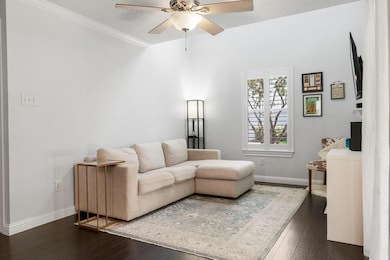 Living room featuring dark wood finished floors, a textured ceiling, crown molding, and a ceiling fan