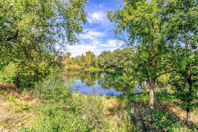 Peaceful natural setting overlooking a sparkling pond surrounded by mature trees.