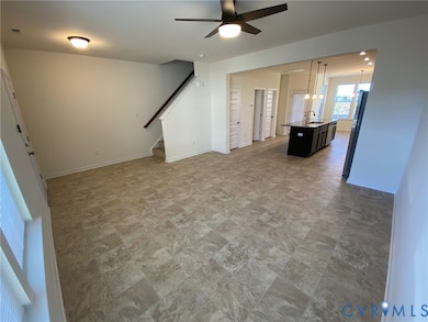 Unfurnished living room featuring ceiling fan, stone finish floors, and stairs