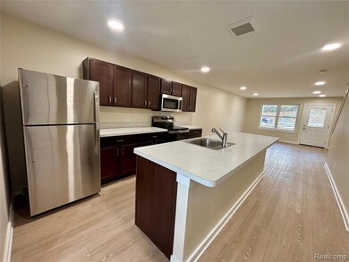 Kitchen featuring appliances with stainless steel finishes, dark brown cabinetry, light countertops, light wood finished floors, and recessed lighting