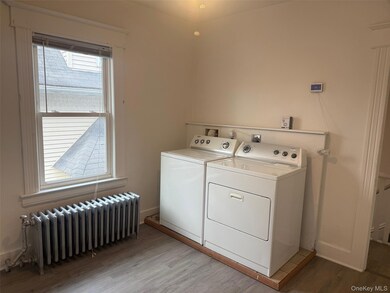 Laundry room featuring radiator, light wood finished floors, and washer and clothes dryer