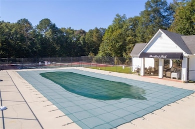 Community pool with view of scattered trees and a patio
