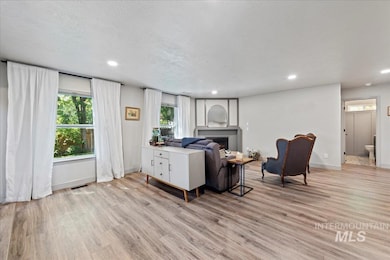 Living area featuring light wood-style floors, plenty of natural light, a fireplace, recessed lighting, and a textured ceiling