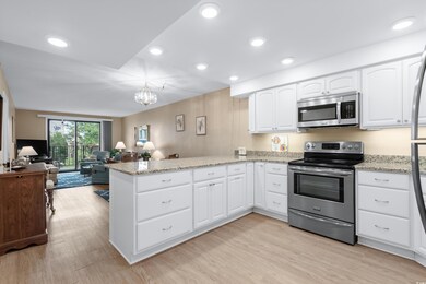 Kitchen with a peninsula, white cabinetry, open fl