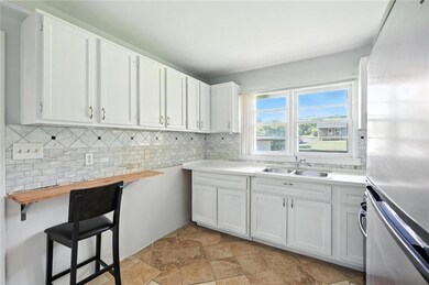 Kitchen featuring stainless steel fridge, tasteful backsplash, white cabinets, light stone finish flooring, and butcher block countertops