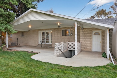 Back of house featuring french doors, a patio area, brick siding, and a lawn
