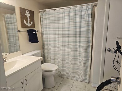 Full bath with toilet, tile patterned floors, vani