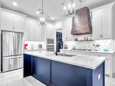 Kitchen featuring appliances with stainless steel finishes, premium range hood, a chandelier, recessed lighting, and tasteful backsplash