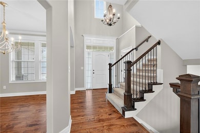 Entrance foyer featuring a chandelier, dark wood-style floors, a high ceiling, and arched walkways