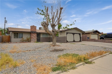 Single story home featuring driveway, a garage, a chimney, and stucco siding