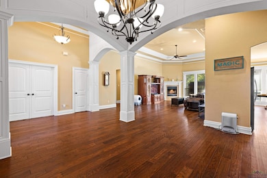 Living area with arched walkways, ornate columns, a lit fireplace, a high ceiling, and recessed lighting
