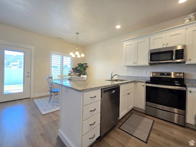 Kitchen with stainless steel appliances, white cabinetry, dark wood-style flooring, and recessed lighting