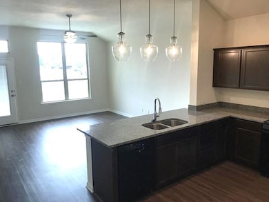 Kitchen featuring light stone counters, a sink, a