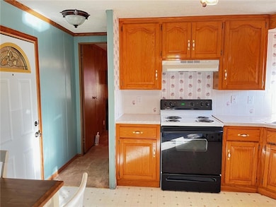 Kitchen featuring electric range, light countertops, brown cabinets, ornamental molding, and under cabinet range hood