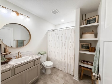 Bathroom with curtained shower, a textured ceiling, and vanity