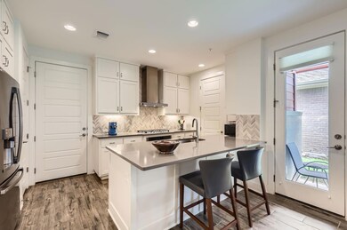 Kitchen featuring wall chimney exhaust hood, stai