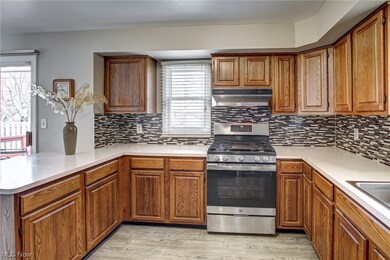 Kitchen featuring kitchen peninsula, gas range, backsplash, and light wood-type flooring