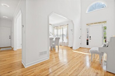 Foyer featuring healthy amount of natural light, arched walkways, light wood-style floors, crown molding, and baseboards