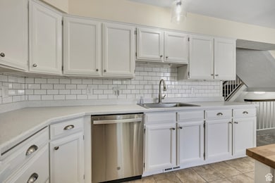 Kitchen with dishwasher, white cabinetry, and light countertops