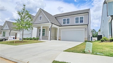 View of front facade featuring board and batten siding, a garage, driveway, stone siding, and a front yard
