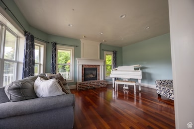 Living room featuring dark wood-style floors, a fireplace, and recessed lighting