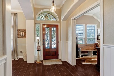 Making our way inside, you will see the beautiful front foyer area, boasting wood-look tile flooring.  To the right (in this picture) is the home office.  To the left (in this picture) is the formal dining room.  The front door with privacy panels and sidelight, plus arched window above the door, allow light to pour in.