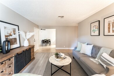 Living room with a textured ceiling, light wood finished floors, and ceiling fan