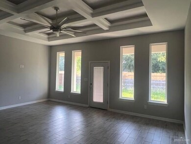 Unfurnished room with coffered ceiling, baseboards, wood finished floors, ceiling fan, and beam ceiling