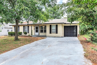 Ranch-style house featuring an attached garage, driveway, a shingled roof, and a front yard