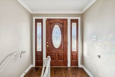 Foyer entrance featuring dark wood-type flooring and crown molding