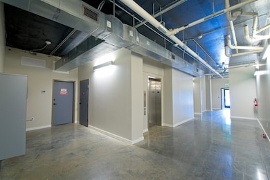 Hallway with elevator, finished concrete floors, and baseboards
