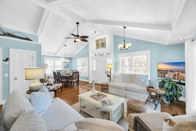 Living area featuring a chandelier, wood finished floors, beam ceiling, high vaulted ceiling, and a ceiling fan