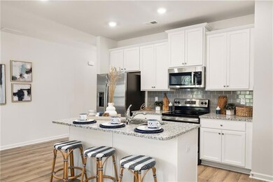 Kitchen with appliances with stainless steel finishes, a breakfast bar area, white cabinetry, decorative backsplash, and recessed lighting
