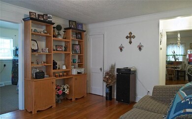 Beautiful hardwoods and wide crown molding! Bedroom 3 on left and hallway to dining room on right.