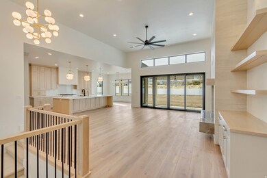 Living room with a chandelier, recessed lighting, light wood finished floors, a high ceiling, and a ceiling fan