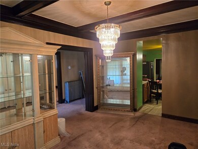 Dining space featuring radiator heating unit, carpet, a chandelier, and beamed ceiling