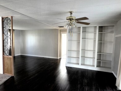 Unfurnished living room featuring dark wood-style floors, a ceiling fan, and built in features