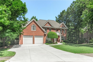 Colonial inspired home featuring an attached garage, driveway, a front lawn, and brick siding