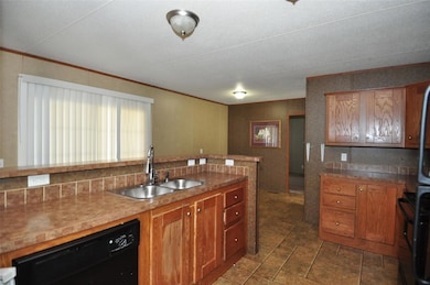 Kitchen with black dishwasher, brown cabinetry, t