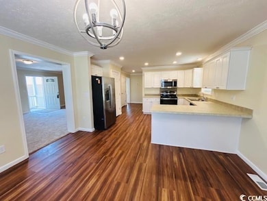 Kitchen with stainless steel appliances, baseboards, dark wood-style floors, light countertops, and a sink