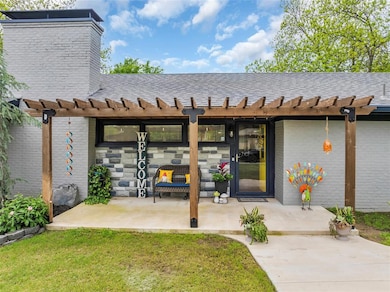 Doorway to property with a patio area, a shingled roof, a pergola, a chimney, and brick siding