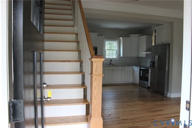 Stairway featuring wood finished floors and ornamental molding