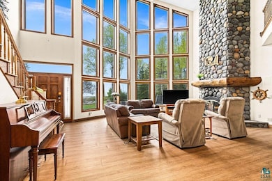 Living area featuring a high ceiling, stairway, light wood finished floors, baseboards, and a fireplace