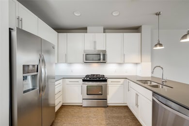Kitchen with stainless steel appliances, a sink, white cabinetry, backsplash, and pendant lighting