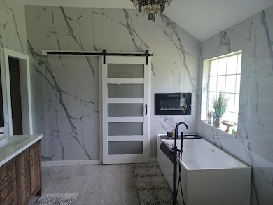 Bathroom with a soaking tub, stone wall, vanity, and tile walls